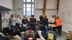 Mehrere kleine Gruppen diskutieren untereinander im Raum des Workshops.